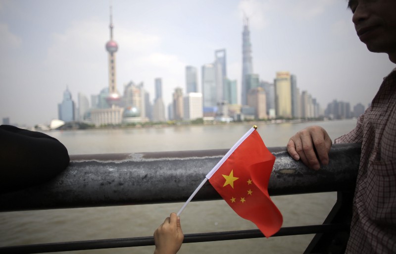 A young holiday goer waves the Chinese national flag on the first day of a week-long National Day holidays in Shanghai, China, Tuesday, Oct. 1, 2013. CREDIT: AP PHOTO/EUGENE HOSHIKO