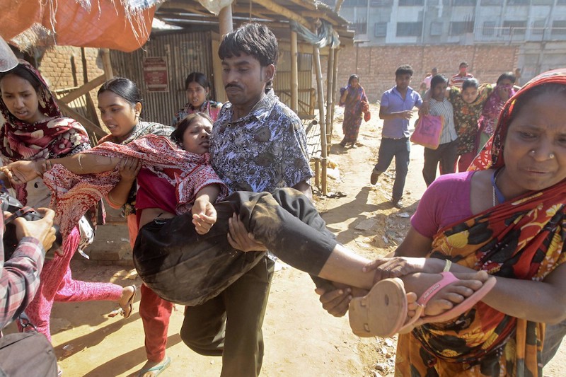 Bangladeshi garment workers assist an injured protester CREDIT: AP