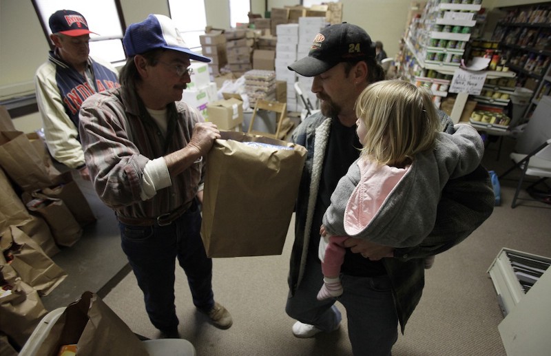 A father picks up food at a pantry CREDIT: AP