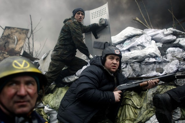 An anti-government protester holds a firearm as he mans a barricade in Kyiv CREDIT: AP Photo/ Marko Drobnjakovic