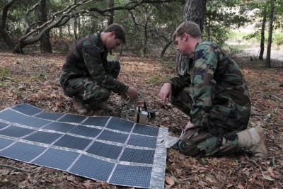 Two officers deploy a portable Power Management Kit, which includes rechargeable batteries and a solar-powered blanket. CREDIT: Petty Officer 2nd Class Paul D. Williams / U.S. Navy