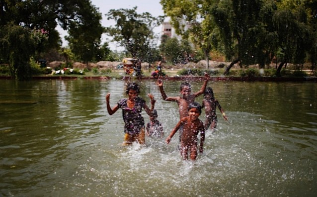 Indian children play in a pond on a hot summer afternoon in New Delhi. CREDIT: A.P. Images