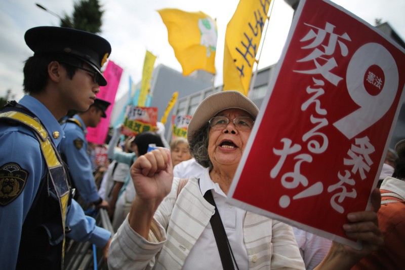 Woman protests against changes to Article 9 o fthe Japanese constitution outside Prime Minister Shinzo Abe’s office CREDIT: AP PHOTO/EUGENE HOSHIKO