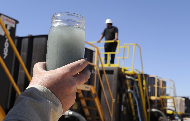 A jar holding waste water from hydraulic fracturing is held up to the light at a recycling site in Midland, Texas, Sept. 24, 2013. With fresh water not as plentiful companies have been looking for ways to recycle their waste. CREDIT: AP PHOTO/PAT SULLIVAN