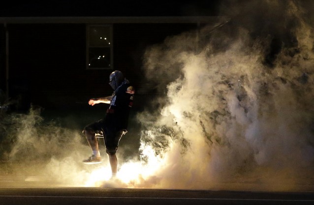 A protester kicks a smoke grenade deployed by police. CREDIT: AP Photo/Jeff Roberson