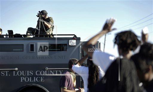 A member of the St. Louis County Police Department points his weapon in the direction of a group of protesters in Ferguson, Mo. on Wednesday, Aug. 13. CREDIT: AP Photo/Jeff Roberson