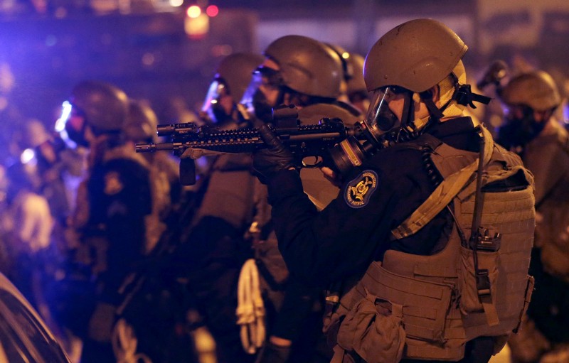 Police advance after tear gas was used to disperse a crowd of protesters in Ferguson, MO on Sunday CREDIT: AP PHOTO/CHARLIE RIEDEL