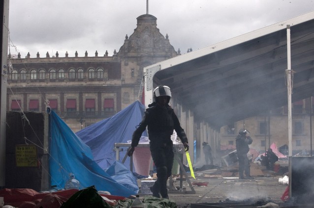 A riot policeman walks through the Zocalo, Mexico City’s main plaza, after a mass eviction of striking teachers CREDIT: AP Photo/Christian Palma