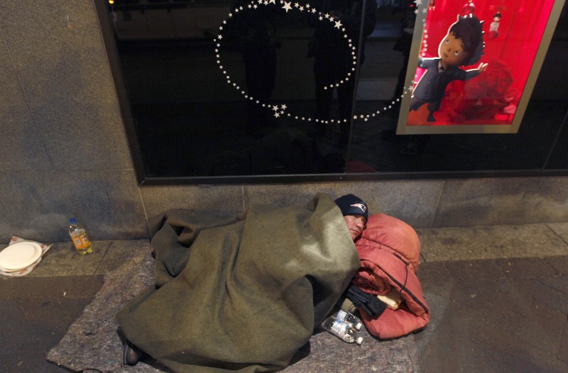 A homeless man sleeps on the street in Boston CREDIT: AP