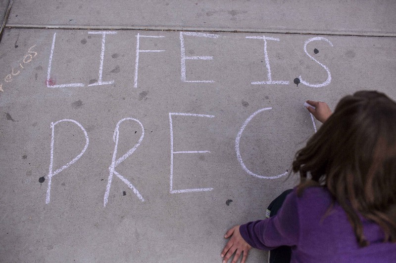 An abortion opponent in favor of a proposed 20-week ban chalks a message that reads “life is precious” in New Mexico CREDIT: AP PHOTO/ JUAN ANTONIO LABRECHE