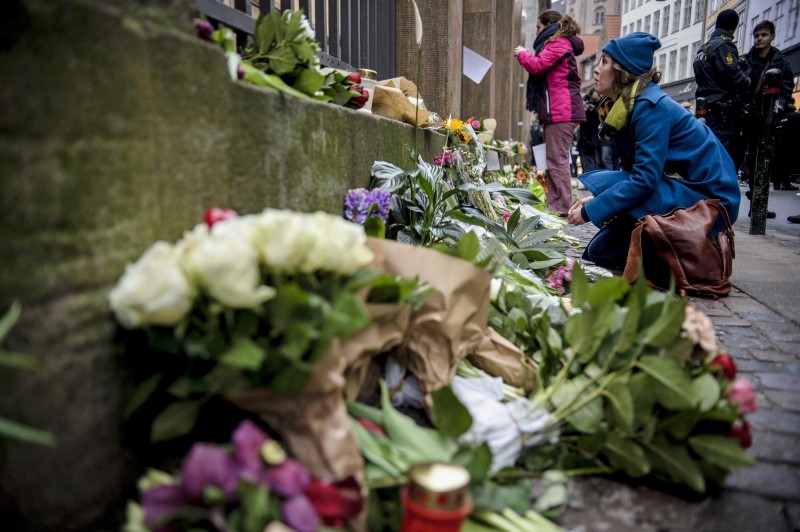 Mourners place flowers beside a Copenhagen synagogue where a guard was killed on Sunday. CREDIT: AP