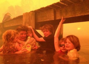 This photo taken by Tim Holmes shows his family clinging to a wooden dock while a wildfire rages on land, Jan. 4, 2013. CREDIT: TIM HOLMES / AP