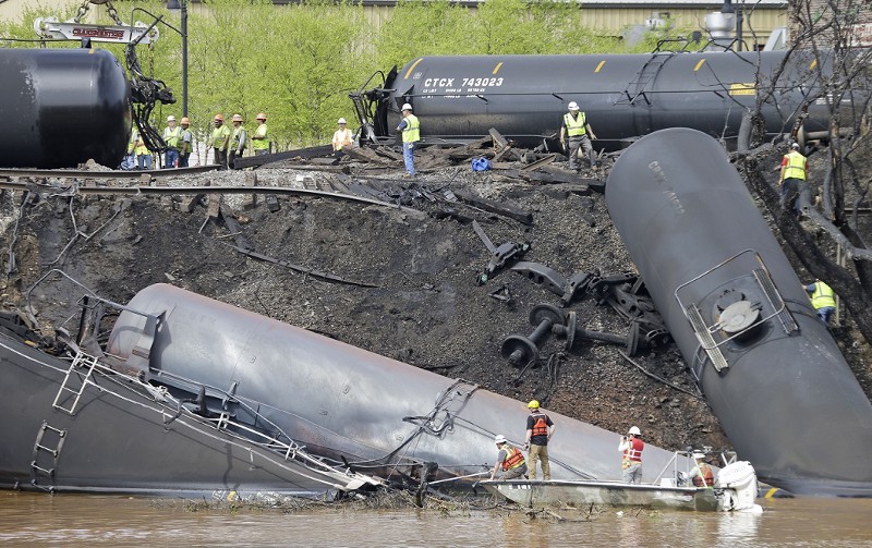 Survey crews in boats look over tanker cars as workers remove damaged tanker cars along the tracks where several CSX tanker cars carrying crude oil derailed and caught fire along the James River near downtown Lynchburg, Va., Thursday, May 1, 2014. CREDIT: AP PHOTO/STEVE HELBER