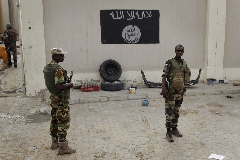 Chadian soldiers stand at a checkpoint in front of a Boko Haram flag the Nigerian city of Damasak, Nigeria, on March 18, 2015. Damasak was flushed of Boko Haram militants last week, and is now controlled by a joint Chadian and Nigerien force. CREDIT: AP