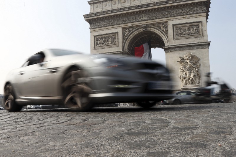 Cars and scooters drive around the Arc de Triomphe, seen in background, in the center Paris, France, Wednesday, March 18, 2015. Paris police have lowered the speed limit and ordered a halt to burning of trash as part of emergency measures triggered by a spike in air pollution, months before the city hosts a major international climate conference. CREDIT: AP PHOTO/FRANCOIS MORI