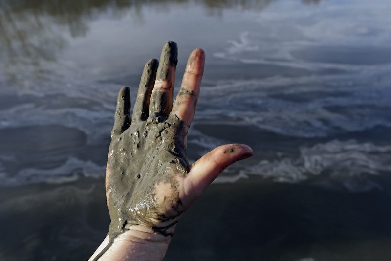 A hand covered with wet coal ash from the Dan River spill in February. CREDIT: AP PHOTO / GERRY BROOME