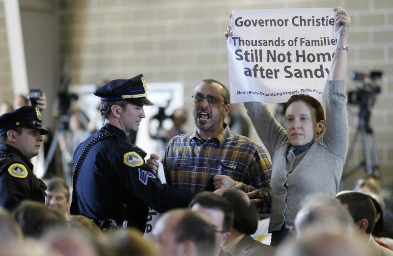 Joe Mangino and fellow protestors are removed from the crowd as New Jersey Gov. Chris Christie speaks during the Iowa Agriculture Summit, Saturday, March 7, 2015, in Des Moines, Iowa. CREDIT: AP PHOTO/CHARLIE NEIBERGALL