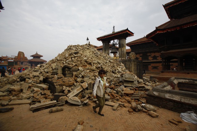 A Nepalese woman walks past a collapsed temple in Bhaktapur Durbar Square after an earthquake in Kathmandu, Nepal, Sunday, April 26, 2015. CREDIT: AP