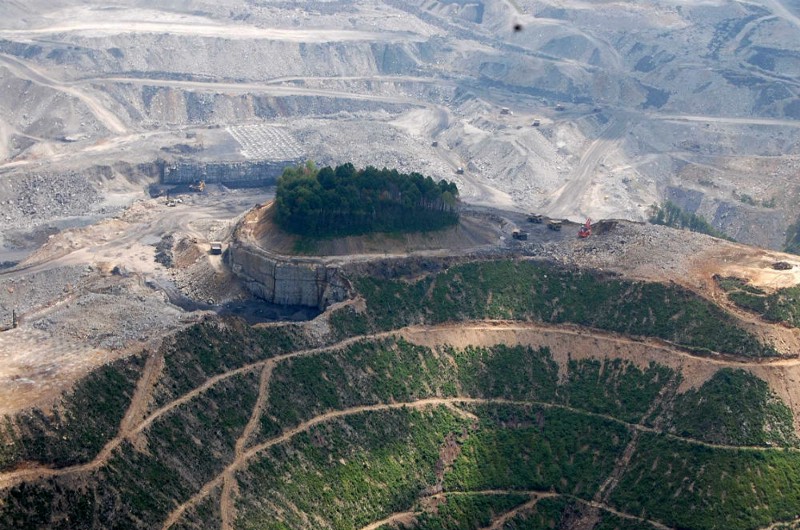 In this June 2010 aerial photo released Thursday, Aug. 29, 2013 by Ohio Valley Environmental Coalition, mining equipment is seen on a mountain top near a cemetery is inside the forested area on that tiny knob of land in the middle of the mine complex. CREDIT: AP/MARIA GUNNOE, OHIO VALLEY ENVIRONMENTAL COALITION