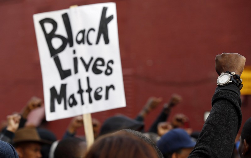 Marchers raise their fists in the air near the Baltimore Police Department’s Western District police station during a march for Freddie Gray, Wednesday, April 22, 2015, in Baltimore. Gray died from spinal injuries about a week after he was arrested and transported in a police van. CREDIT: AP PHOTO/ALEX BRANDON