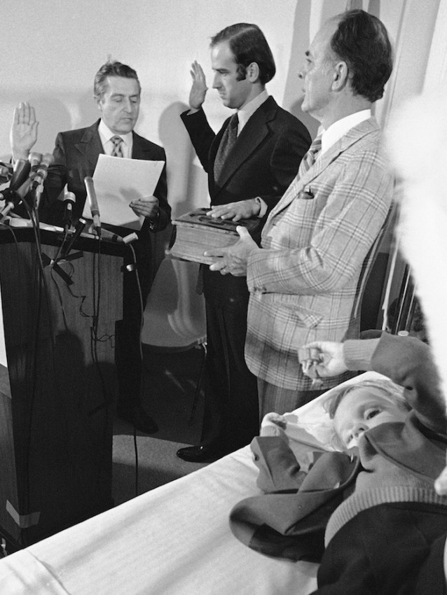 In this Jan. 5, 1973 file photo, four-year-old Beau Biden, foreground, plays near his father, Joe Biden, center, being sworn in as the U.S. senator from Delaware, by Senate Secretary Frank Valeo, left, in ceremonies in a Wilmington hospital. Beau was injured in an accident that killed his mother and sister in December 1972. Mrs. Biden’s father, Robert Hunter, holds the Bible.