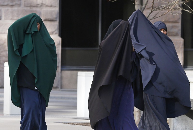 Members of Minnesota’s Somali community cover their faces as they arrive Thursday, April 23, 2015, for a detention hearing in federal court in St. Paul, Minn. for four of the six Minnesotans who are accused of plotting to travel to Syria to join the Islamic State group. CREDIT: AP