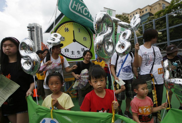 Protesters from various Labor unions and their children hold balloons in the shape of a number eight, representing the 8 working hours a day with a float of a mock clock that advises people work only one third of a day during a march to mark May Day in Hong Kong Friday, May 1, 2015. Hundreds of people staged a rally to demand better workers’ rights and call for standard working hours. CREDIT: AP