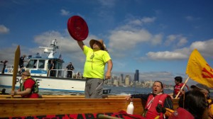 Justin Finkbonner, the Lummi Youth Canoe Family skipper, stands in his canoe in front of the Arctic-bound Polar Pioneer. CREDIT: Emily Johnston