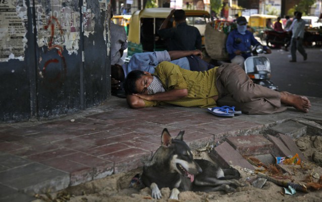 An Indian man rests near a dog under an over head bridge on a hot day at a wholesale market in Ahmadabad, India, Tuesday, May 19, 2015. CREDIT: AP Photo/Ajit Solanki