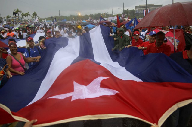 Cubans hold a representation of their national flag as they march in the rain in Revolution Square, marking May Day in Havana, Cuba, Friday, May 1, 2015. Thousands of people converged on the plaza for the traditional march, led this year by President Raul Castro and Venezuelan President Nicolas Maduro. CREDIT: AP