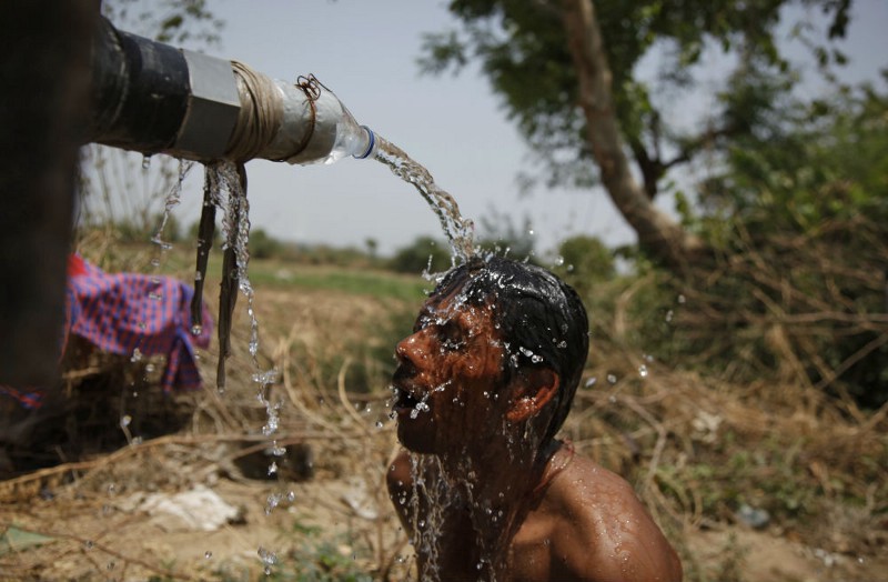 An Indian man takes bath under the tap of a water tanker on a hot day in Ahmadabad, India, Thursday, May 21, 2015. CREDIT: AP PHOTO/AJIT SOLANKI