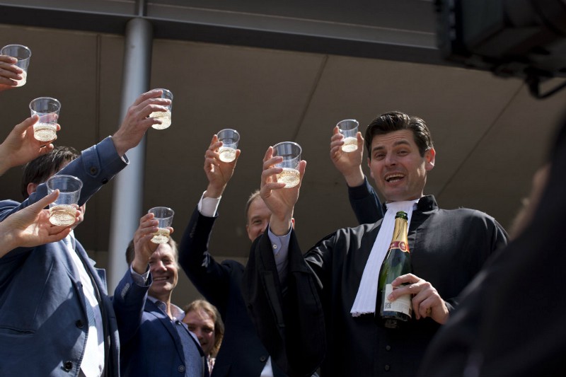 Urgenda Foundation lawyer Roger Cox, right, proposes a toast on the steps of the court house in a scene setup by TV in The Hague, Netherlands, Wednesday, June 24, 2015. A Dutch court has ordered the government to cut the country’s greenhouse gas emissions by at least 25 percent by 2020 in a groundbreaking climate case that activists hope will set a worldwide precedent. The Hague District Court made the ruling Wednesday in a case brought by a sustainability organization on behalf of some 900 citizens, claiming that the the government has a duty of care to protect its citizens against looming dangers. CREDIT: AP PHOTO/PETER DEJONG