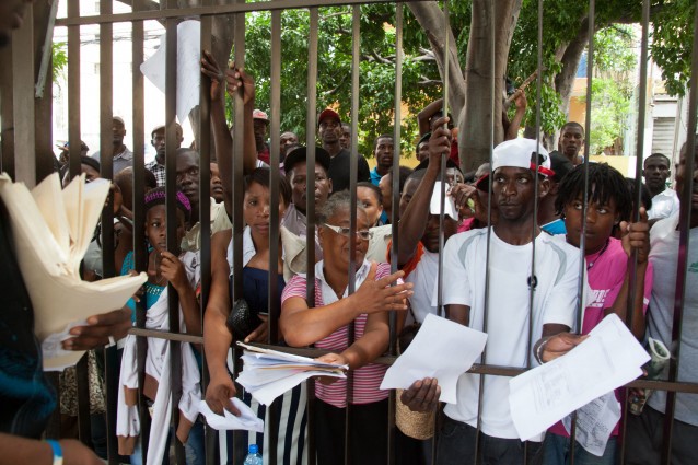 Migrants, mostly Haitians, show officers their documents as they wait their turn to register for legal residency at the Interior Ministry in Santo Domingo, Dominican Republic. CREDIT: AP