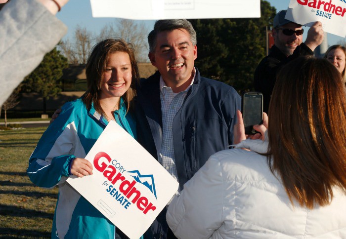 Cory Gardner, right, Republican candidate for the U.S. Senate seat in Colorado, poses for photograph with one of his supporters waving placards. CREDIT: AP PHOTO/DAVID ZALUBOWSKI