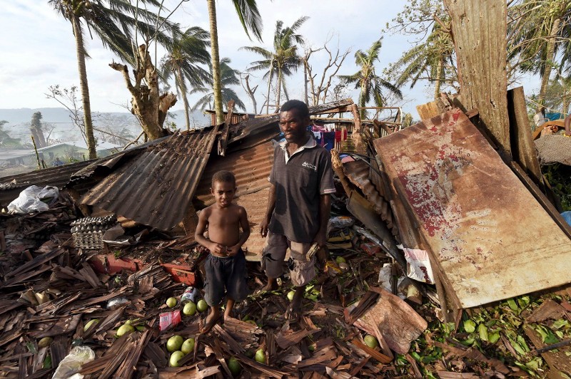 A father and son stand among the remains of their destroyed home in Port Vila, Vanuatu in the aftermath of Cyclone Pam Monday, March 16, 2015.