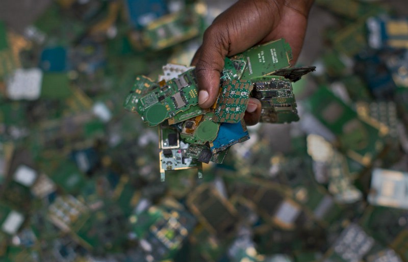 In this photo taken Monday, Aug. 18, 2014, a worker gathers handfuls of cellphone printed circuit boards from a pile to put in a sack for recycling, at the East African Compliant Recycling facility in Machakos, near Nairobi, in Kenya. CREDIT: AP PHOTO/BEN CURTIS