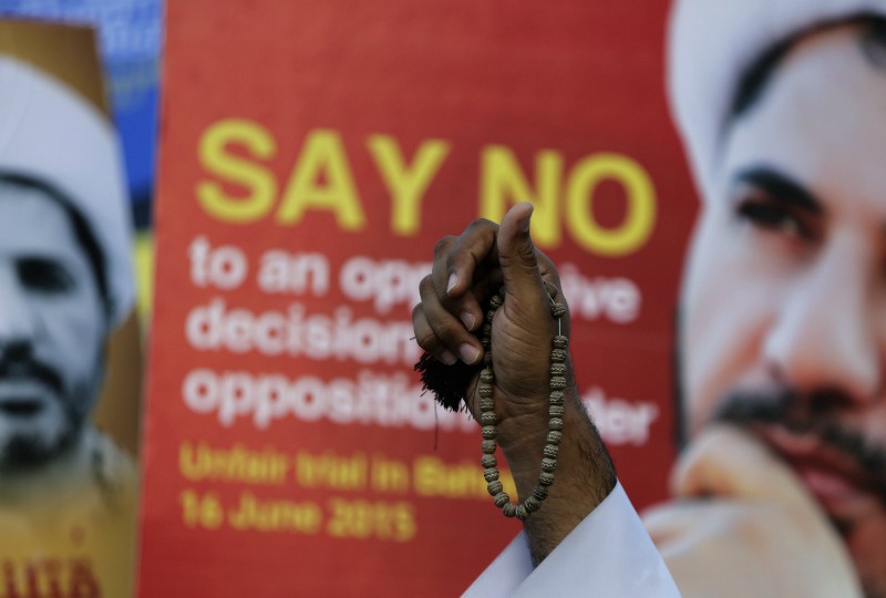 A man holding prayer beads chants anti-government slogans against the conviction of Shiite cleric Sheikh Ali Salman, seen on signs, over insult charges, during a protest in Manama, Bahrain, Tuesday, June 16, 2015. CREDIT: AP