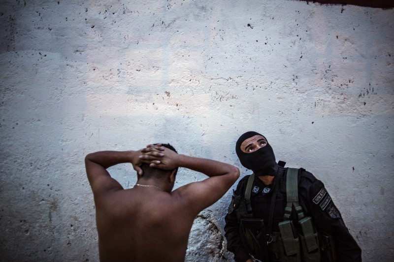 A member of the fast response police units, known as Halcones, stands next to a detained man, suspected of gang associations, in San Salvador, El Salvador, Thursday, May 28, 2015. CREDIT: AP PHOTO/MANU BRABO
