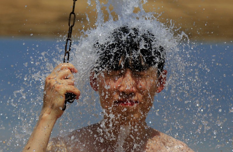 In this Sunday, Aug. 16, 2015 file photo, a boy takes a shower after bathing in the Dead Sea, near the West Bank city of Jericho. The region experienced another heat wave with temperatures in reaching well over 40 degrees Celsius (104 Fahrenheit) in some areas. CREDIT: AP PHOTO/HATEM MOUSSA, FILE