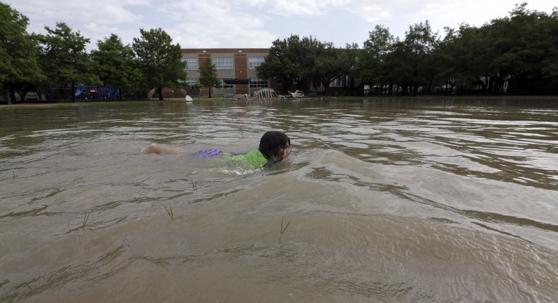 Joselyn Ramirez swims in a flooded school playground in Houston, May 26, 2015, following severe storms. CREDIT: AP PHOTO/DAVID J. PHILLIP