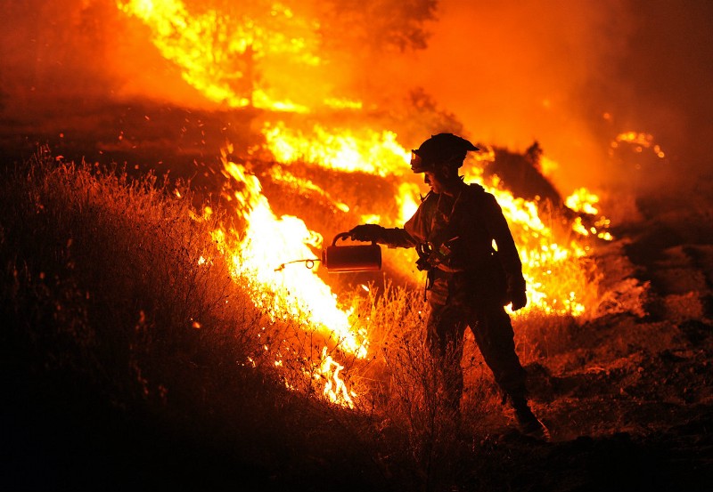 CalFire firefighter Bo Santiago lights a backfire as the Rocky fire burns near Clearlake, Calif., on Monday, Aug. 3, 2015. The fire has charred more than 60,000 acres and destroyed at least 24 residences. CREDIT: AP PHOTO/JOSH EDELSON