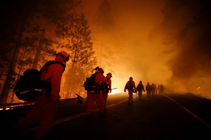 In this Aug. 25, 2013, file photo, inmate firefighters walk along Highway 120 after a burnout operation as firefighters continue to battle the Rim Fire near Yosemite National Park. CREDIT: AP PHOTO/JAE C. HONG, FILE