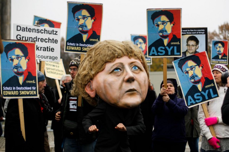 German protester wears a mask depicting German Chancellor Angela Merkel during an anti-government surveillance demonstration in 2013. CREDIT: AP PHOTO/MARKUS SCHREIBER