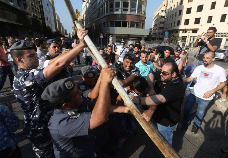Lebanese activists, right, clash with policemen, left, as they try to cross to the government house, as riot police spray them by water during a protest against the ongoing trash crisis, in downtown Beirut, Lebanon, Wednesday, Aug. 19, 2015. Lebanon’s health minister says the country is on the brink of a “major health disaster” unless an immediate solution is found for its mounting trash problem. Garbage has been collecting on the streets in Lebanon for the past month amid government paralysis and inability to agree on a solution after Beirut’s main landfill was closed down. CREDIT: AP Photo/Bilal Hussein