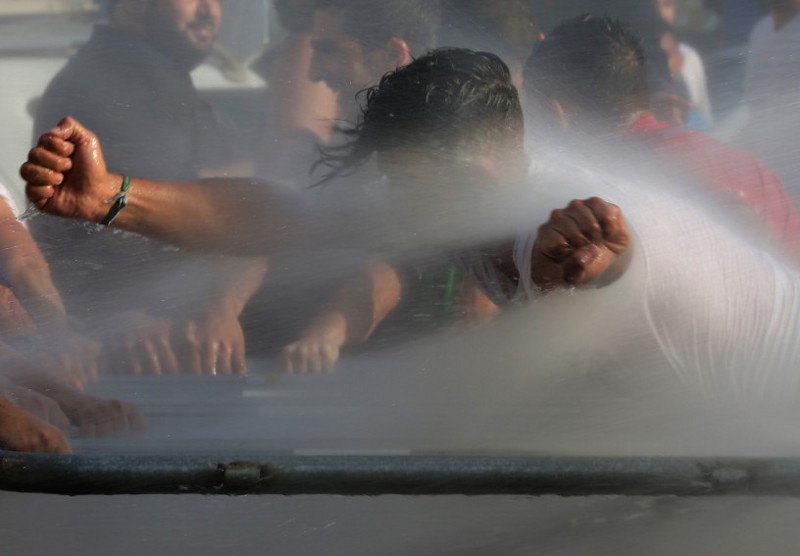 Lebanese activists are sprayed with water as they try to cross to the government house. CREDIT: AP Photo/Hussein Malla