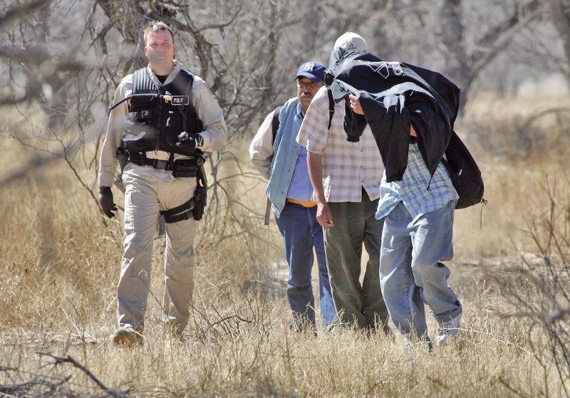 A Customs and Border Protection air officer, left, escorts a group of suspected undocumented immigrants to Border Patrol agents in 2006 in Arizona. CREDIT: AP PHOTO/MATT YORK