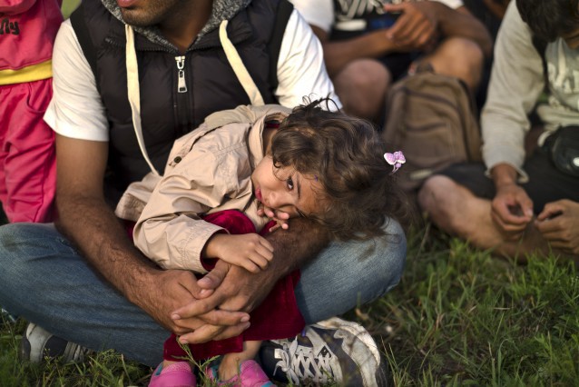 Afghan girl Parisa Sayed Jalil, 4, rests on her father’s lap in a field, while they and others are detained by Hungarian police on horses for sneaking through Hungary’s border fence with Serbia in Asotthalom, southern Hungary, Wednesday, Sept. 16, 2015. CREDIT: AP Photo/Muhammed Muheisen