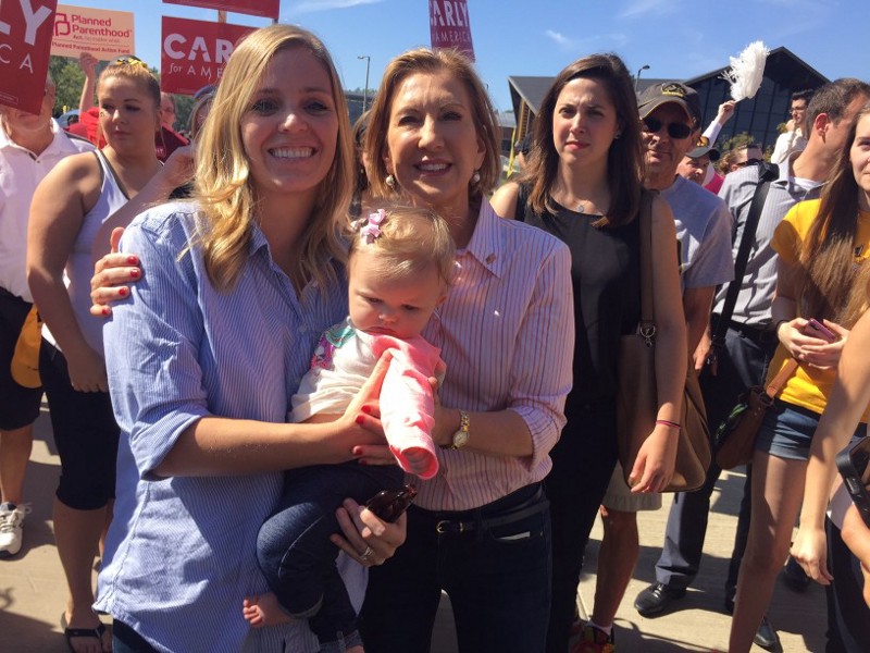 Carly Fiorina holds a baby while Planned Parenthood supporters protest her during an event in Iowa City on Saturday. CREDIT: Emily Atkin
