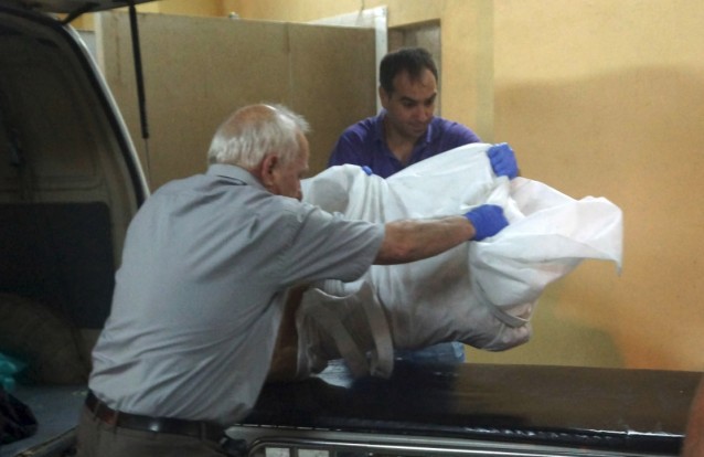 Funeral service employees handle the body of a child brought to a morgue on the southeastern Greek island of Rhodes, Monday, Sept. 14, 2015. CREDIT: Argiris Mantikos/Eurokinissi via AP