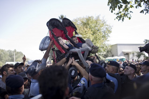 People lift two children that sit in a twin stroller as they try to get them to safety amid scuffles between migrants and Croatian police officers in Tovarnik, Croatia, Thursday, Sept. 17, 2015 CREDIT: AP Photo/Marko Drobnjakovic